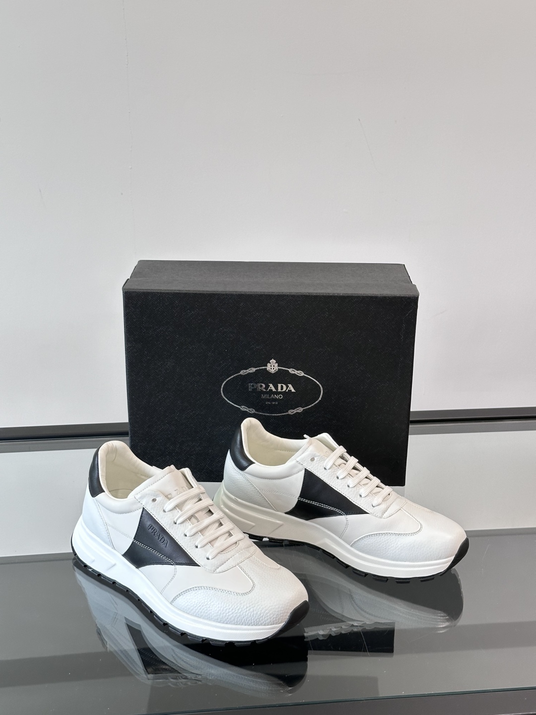 Prada/普拉达 男士新款运动休闲鞋，这款运动鞋鞋面采用进口小牛皮。外侧饰以彩色经典三角图案，真皮内里