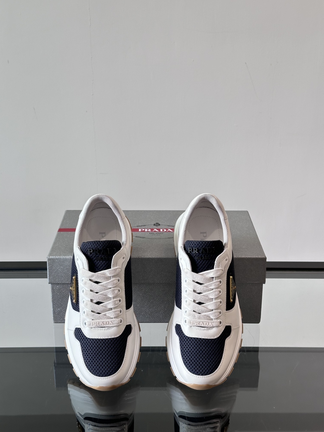 Prada/普拉达 男士新款运动休闲鞋，这款运动鞋鞋面采用进口小牛皮拼接透气网面，外侧饰以P家经典金属三