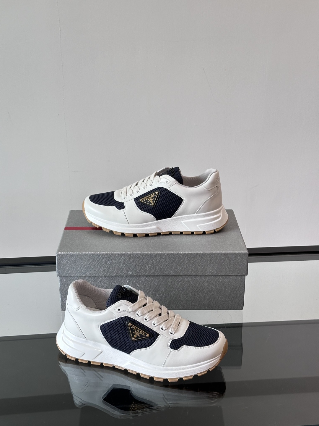 Prada/普拉达 男士新款运动休闲鞋，这款运动鞋鞋面采用进口小牛皮拼接透气网面，外侧饰以P家经典金属三