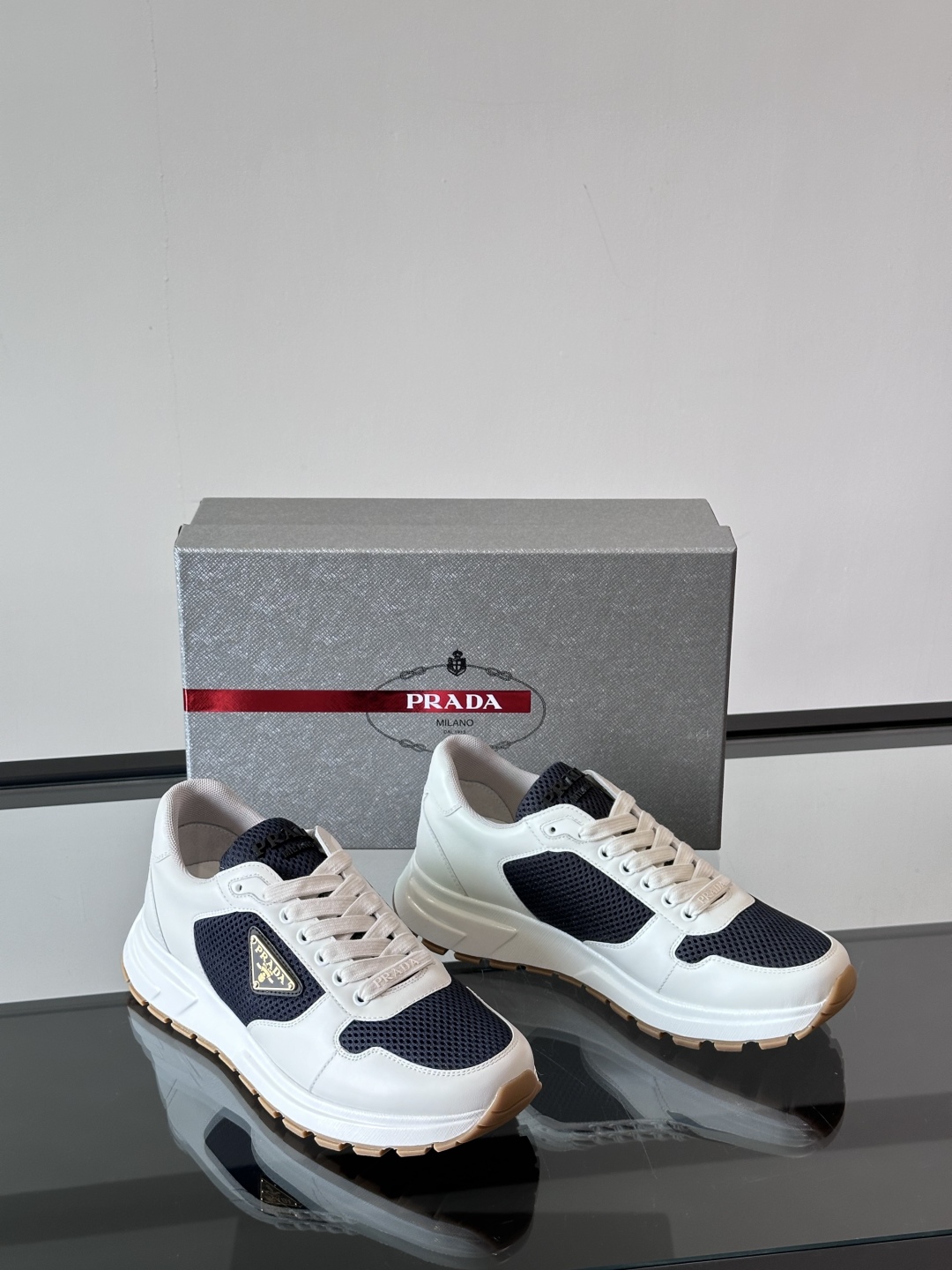 Prada/普拉达 男士新款运动休闲鞋，这款运动鞋鞋面采用进口小牛皮拼接透气网面，外侧饰以P家经典金属三
