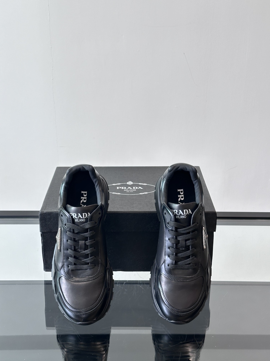 Prada/普拉达 男士新款运动休闲鞋，这款运动鞋鞋面采用进口小牛皮，外侧饰以P家经典金属三角珐琅徽标，