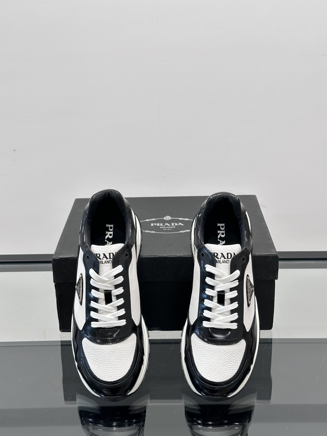 Prada/普拉达 男士新款运动休闲鞋，这款运动鞋鞋面采用进口小牛皮，外侧饰以P家经典金属三角珐琅徽标，
