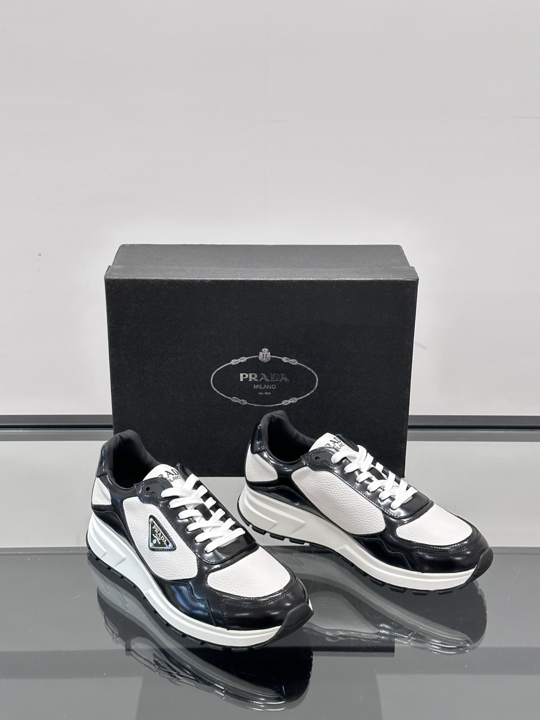 Prada/普拉达 男士新款运动休闲鞋，这款运动鞋鞋面采用进口小牛皮，外侧饰以P家经典金属三角珐琅徽标，