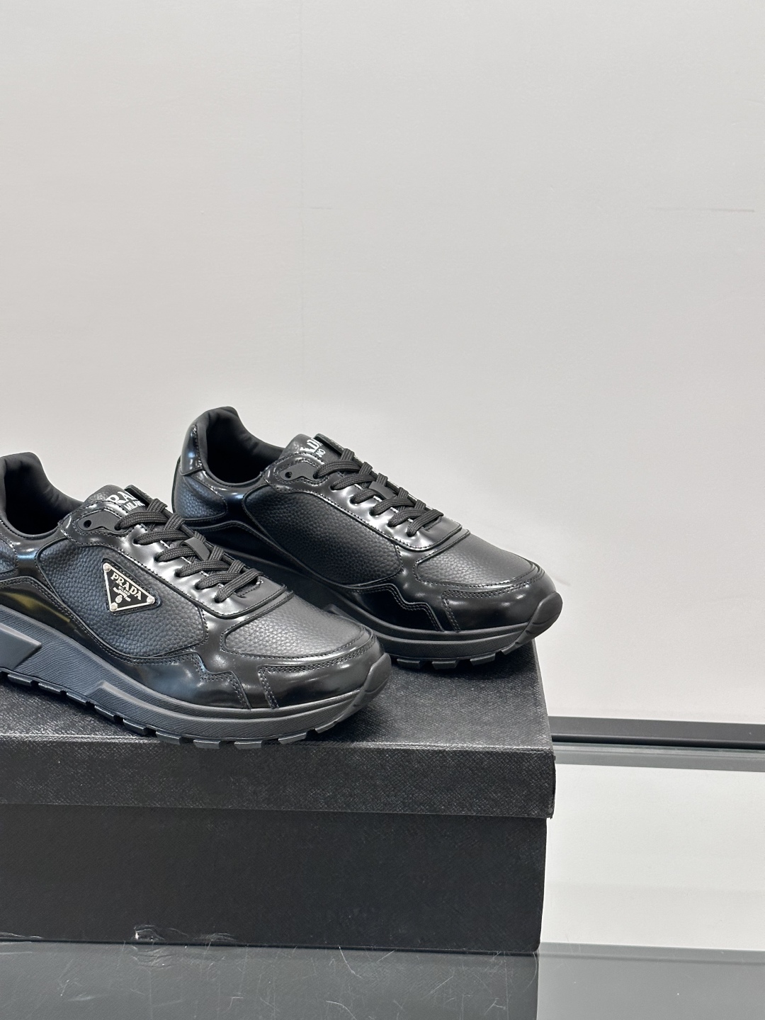 Prada/普拉达 男士新款运动休闲鞋，这款运动鞋鞋面采用进口小牛皮，外侧饰以P家经典金属三角珐琅徽标，