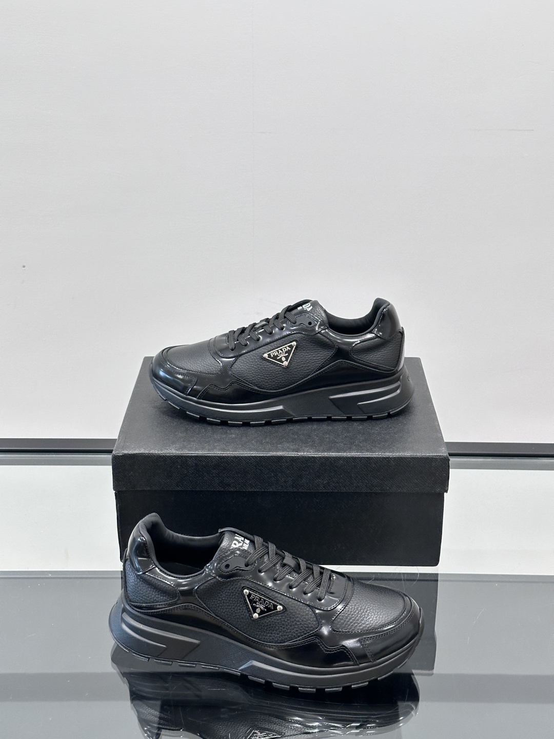 Prada/普拉达 男士新款运动休闲鞋，这款运动鞋鞋面采用进口小牛皮，外侧饰以P家经典金属三角珐琅徽标，