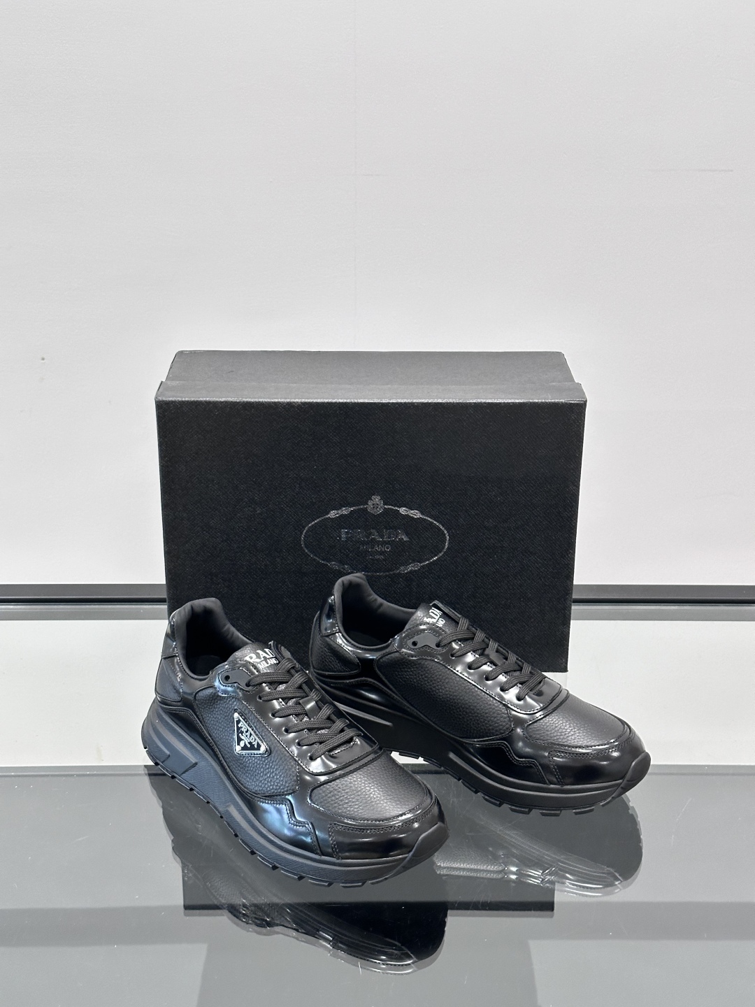 Prada/普拉达 男士新款运动休闲鞋，这款运动鞋鞋面采用进口小牛皮，外侧饰以P家经典金属三角珐琅徽标，