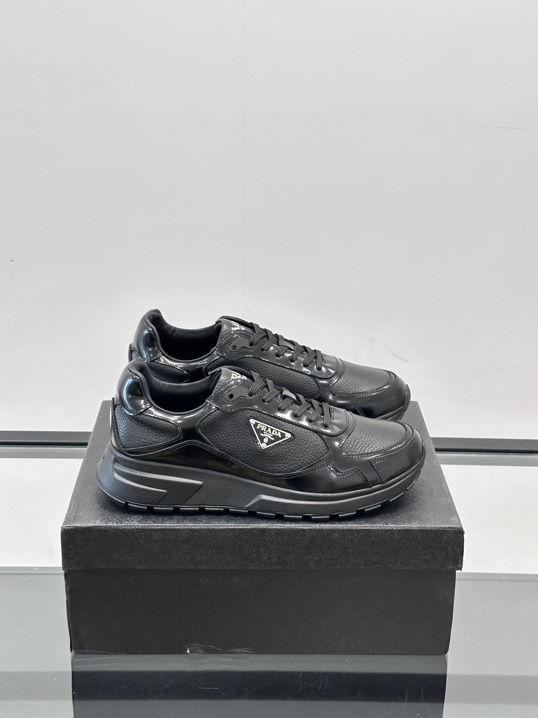 Prada/普拉达 男士新款运动休闲鞋，这款运动鞋鞋面采用进口小牛皮，外侧饰以P家经典金属三角珐琅徽标，