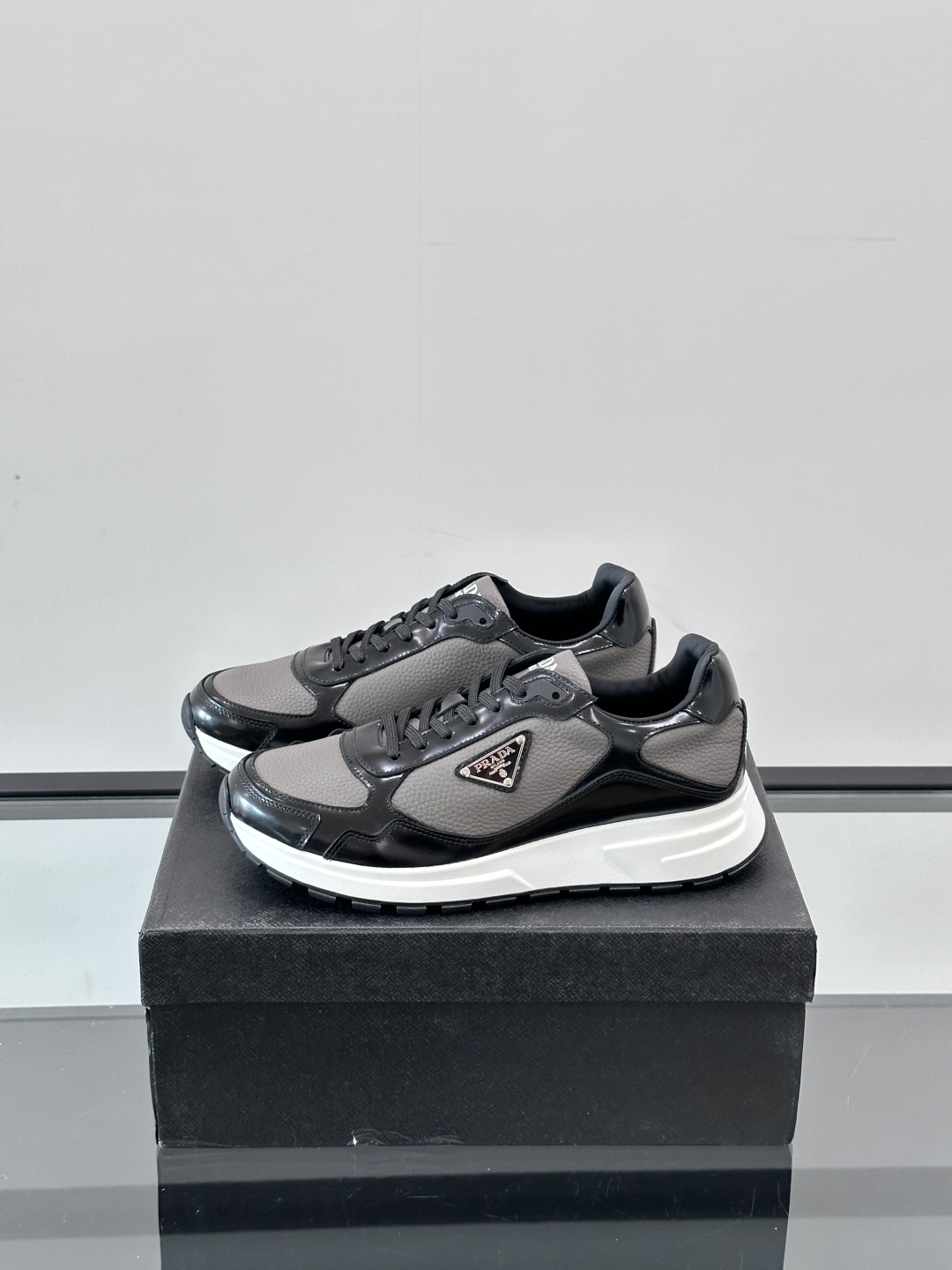 Prada/普拉达 男士新款运动休闲鞋，这款运动鞋鞋面采用进口小牛皮，外侧饰以P家经典金属三角珐琅徽标，