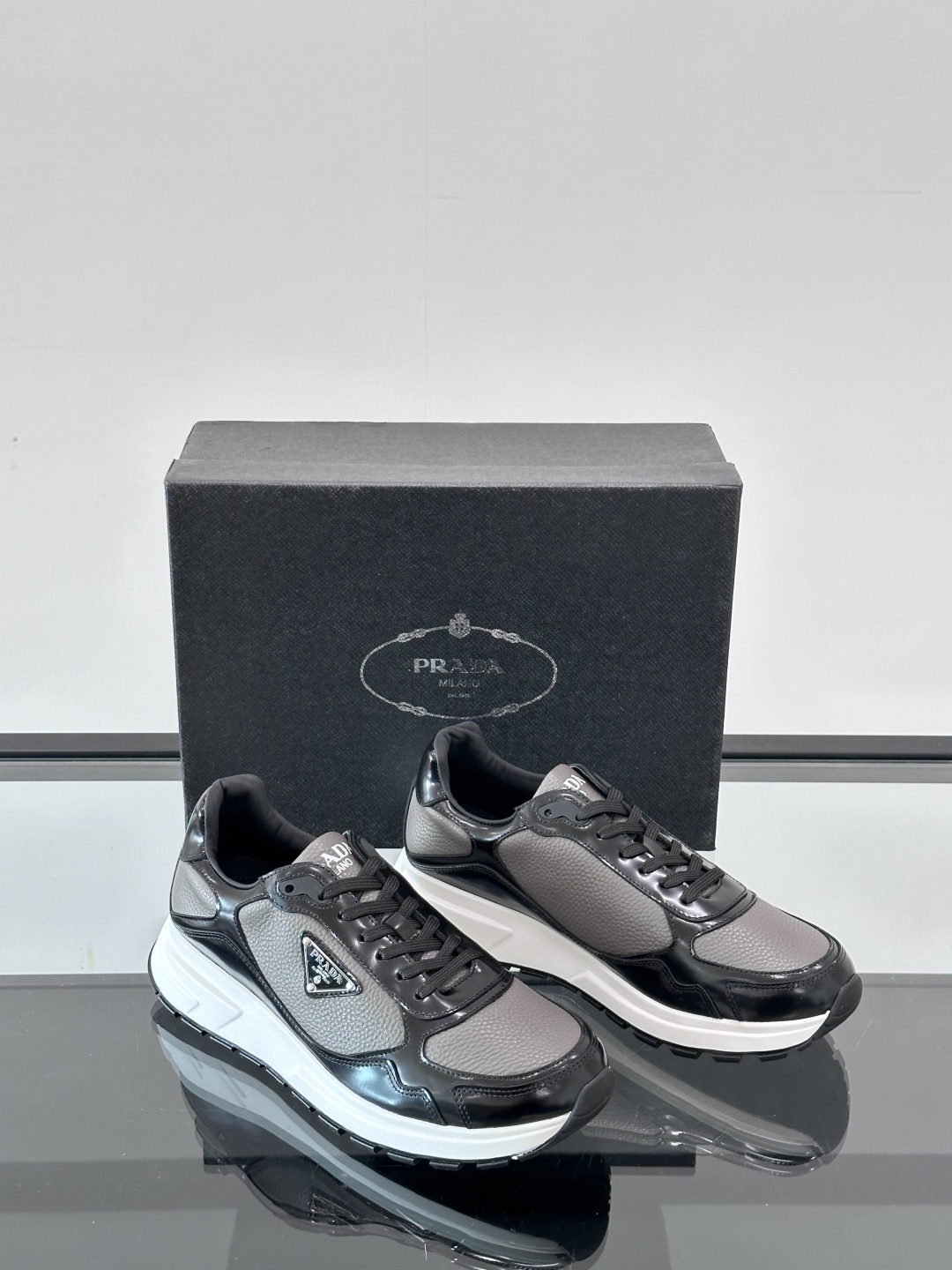Prada/普拉达 男士新款运动休闲鞋，这款运动鞋鞋面采用进口小牛皮，外侧饰以P家经典金属三角珐琅徽标，