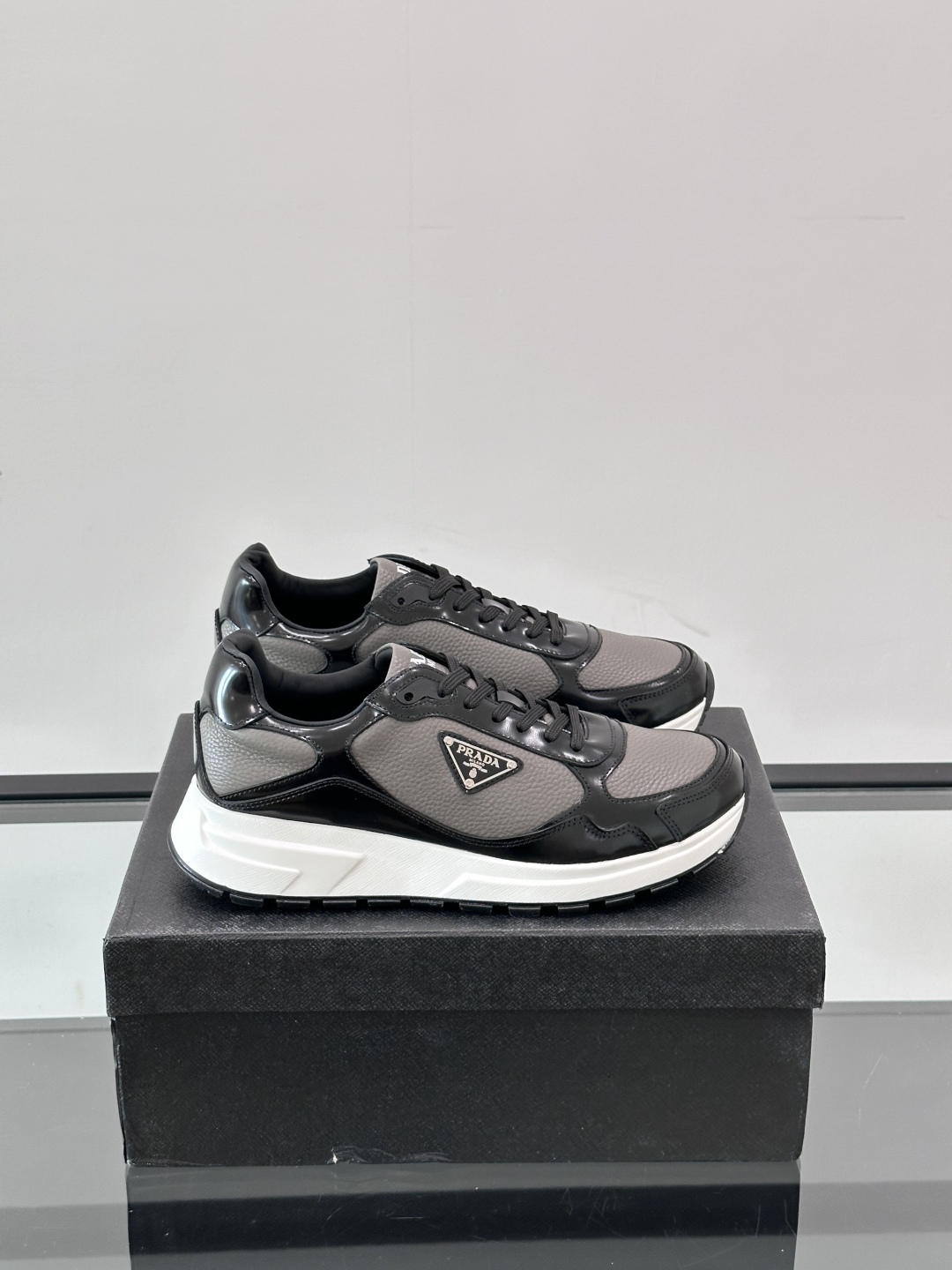 Prada/普拉达 男士新款运动休闲鞋，这款运动鞋鞋面采用进口小牛皮，外侧饰以P家经典金属三角珐琅徽标，