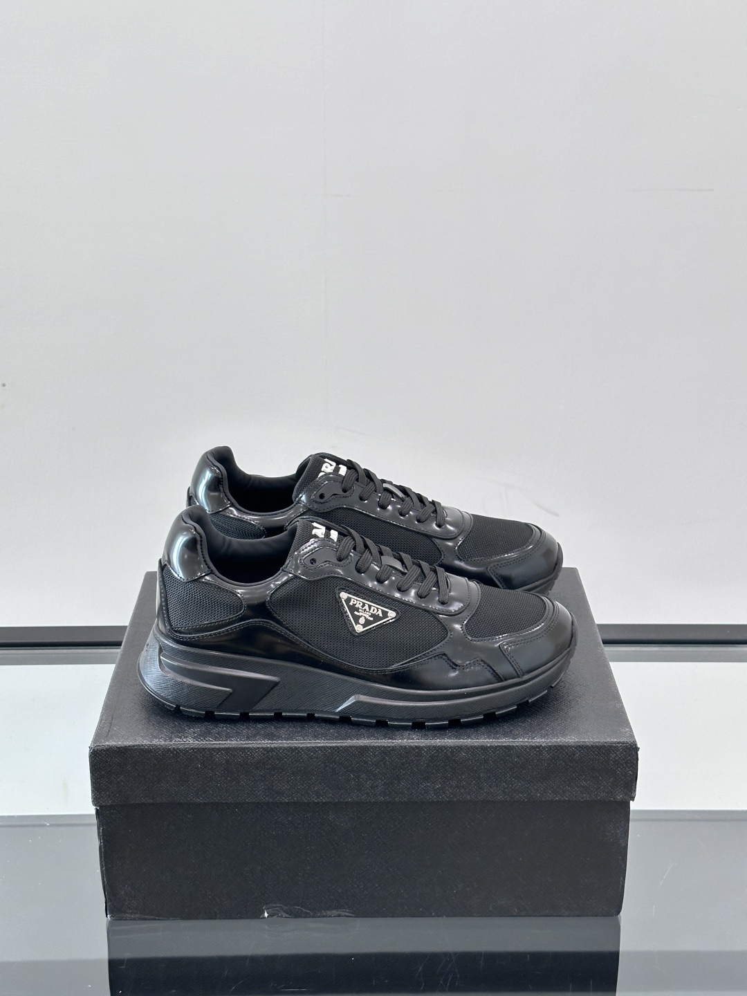 Prada/普拉达 男士新款运动休闲鞋，这款运动鞋鞋面采用进口小牛皮拼接透气网面，外侧饰以P家经典金属三