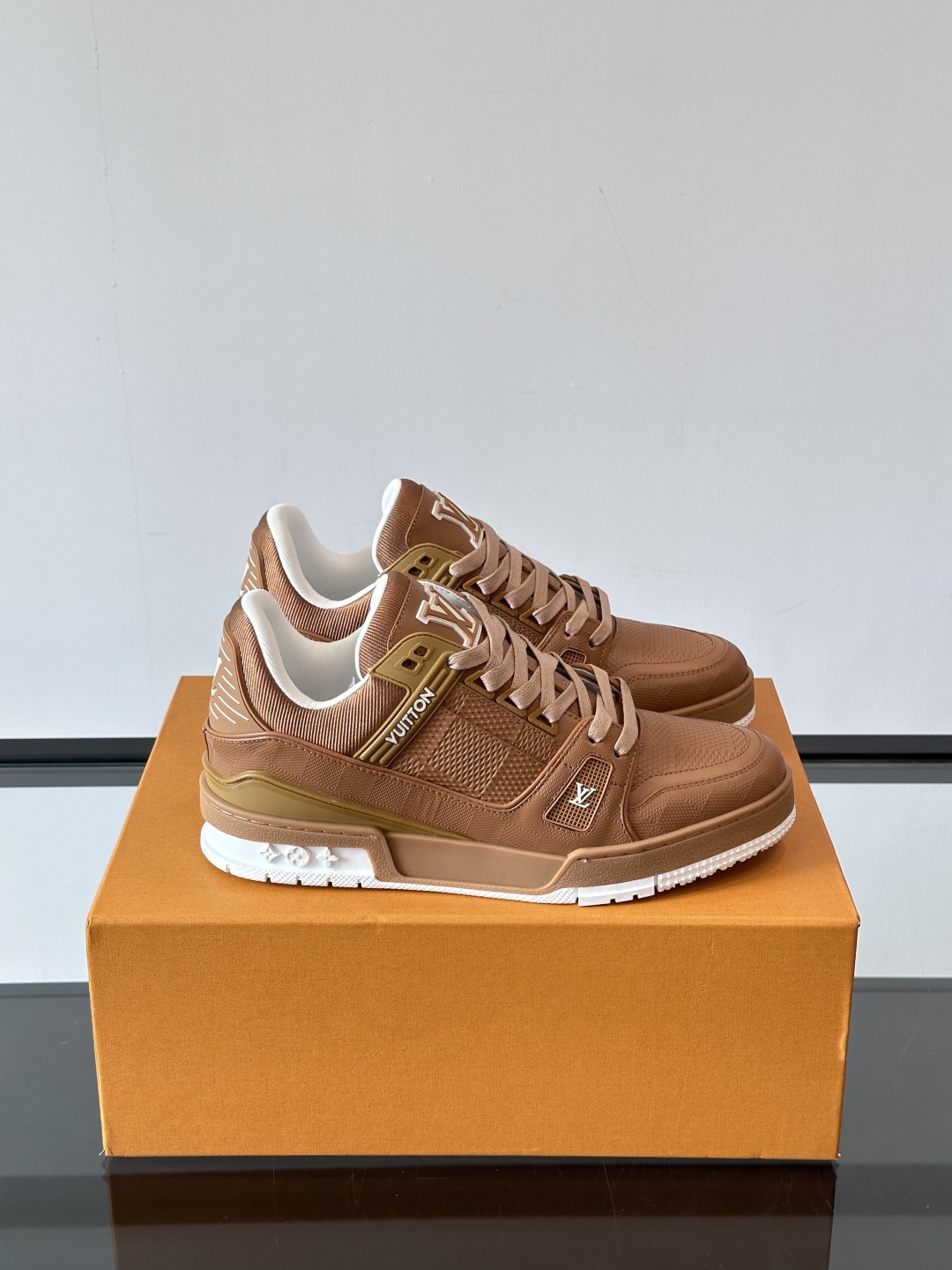  LV Trainer 运动鞋以柔软 Damier 压纹牛皮革续写经典设计。金属端头皮革鞋带点亮雅致鞋身