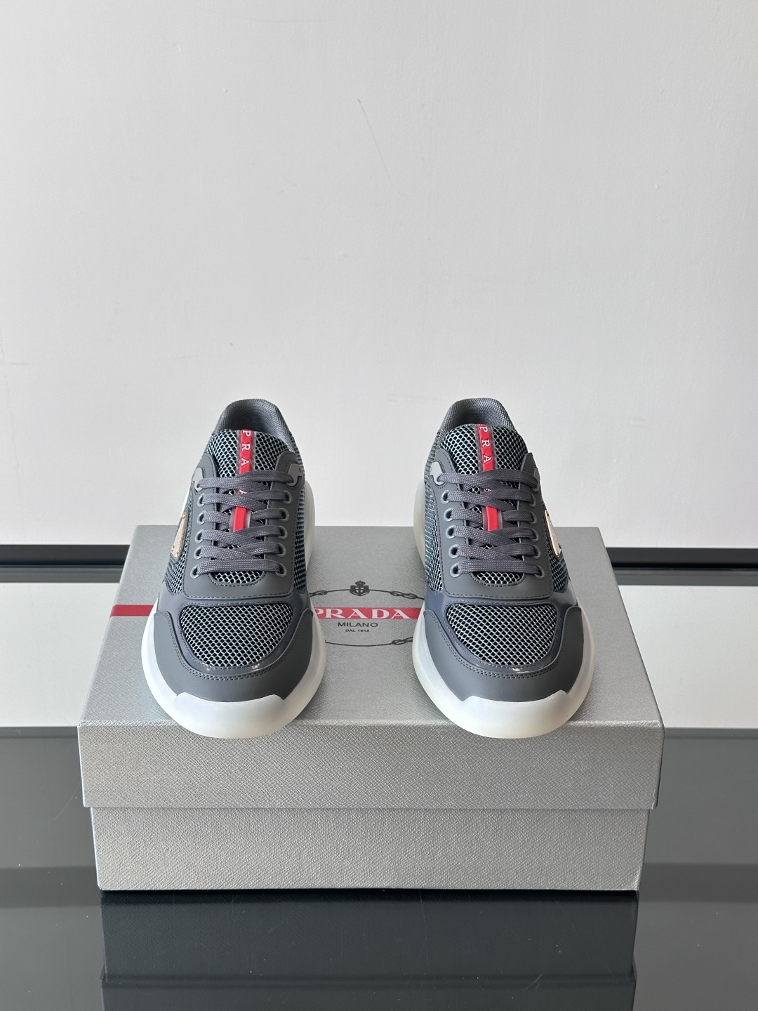 Prada/普拉达 男士新款运动休闲鞋，这款运动鞋鞋面采用进口小牛皮拼接透气网面，外侧饰以P家经典金属三