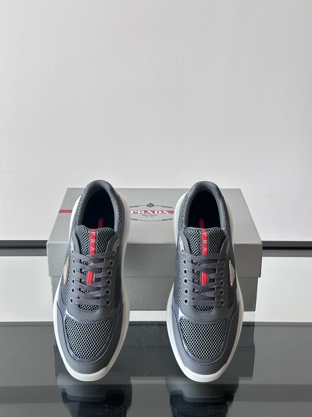 Prada/普拉达 男士新款运动休闲鞋，这款运动鞋鞋面采用进口小牛皮拼接透气网面，外侧饰以P家经典金属三