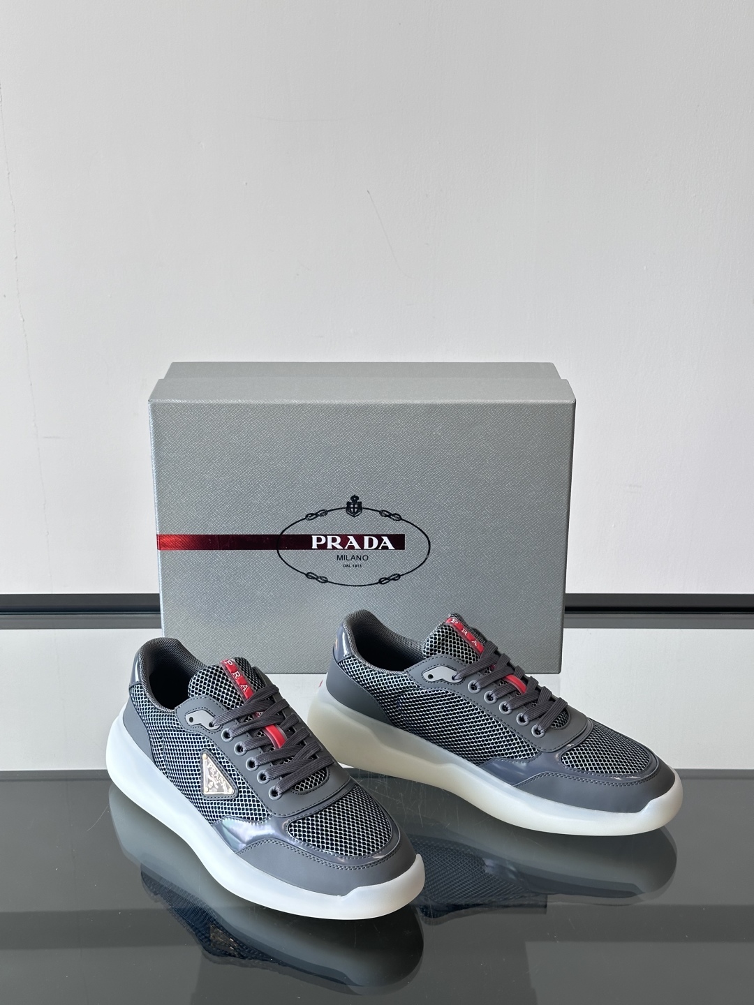Prada/普拉达 男士新款运动休闲鞋，这款运动鞋鞋面采用进口小牛皮拼接透气网面，外侧饰以P家经典金属三