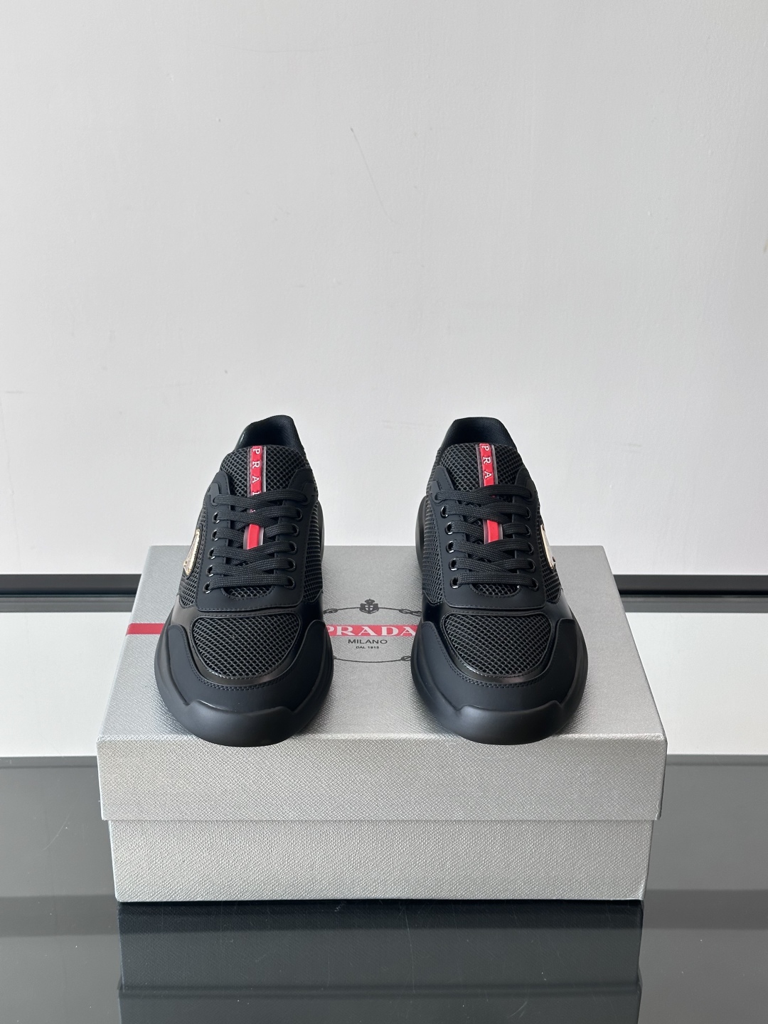 Prada/普拉达 男士新款运动休闲鞋，这款运动鞋鞋面采用进口小牛皮拼接透气网面，外侧饰以P家经典金属三