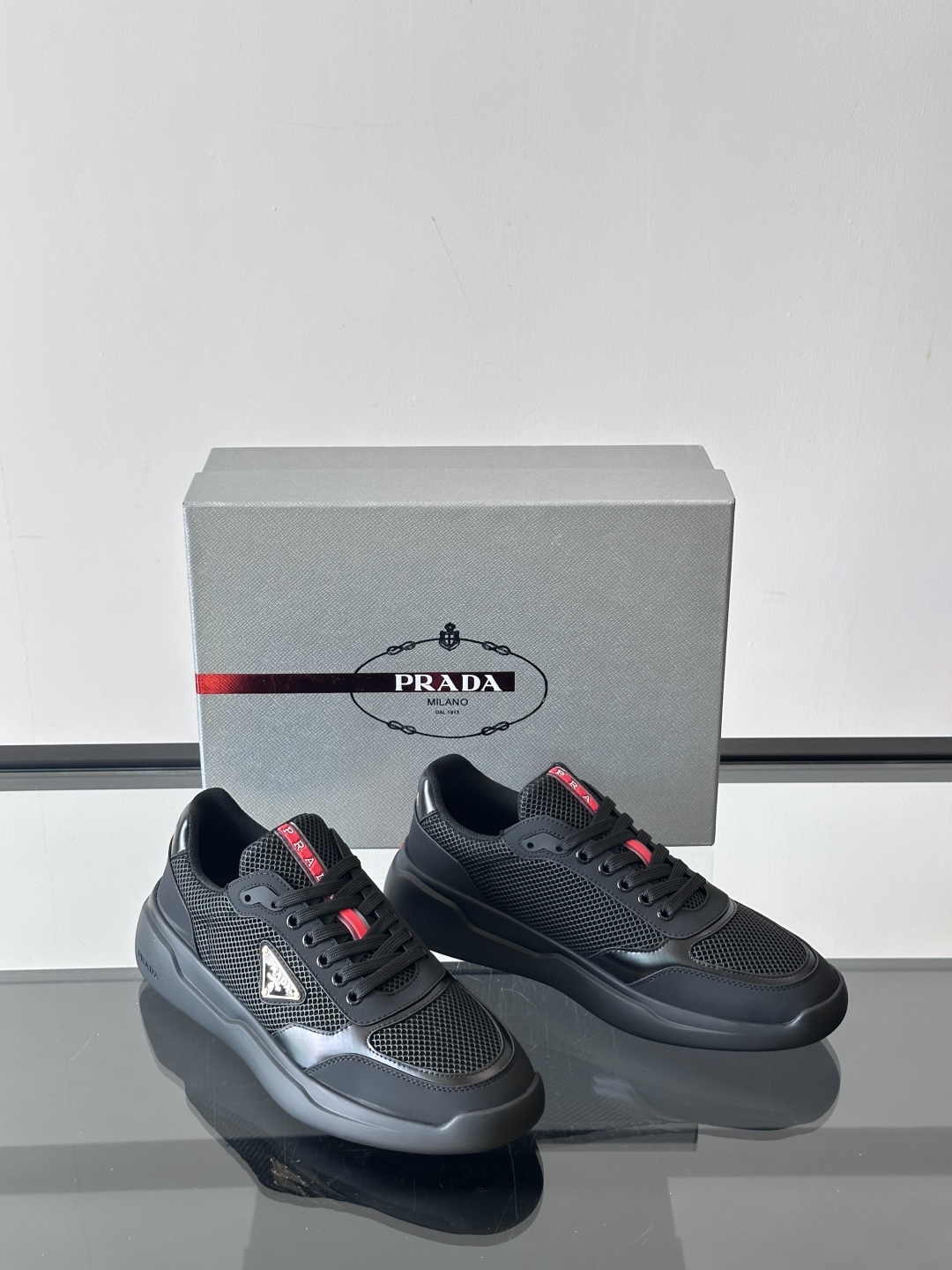 Prada/普拉达 男士新款运动休闲鞋，这款运动鞋鞋面采用进口小牛皮拼接透气网面，外侧饰以P家经典金属三