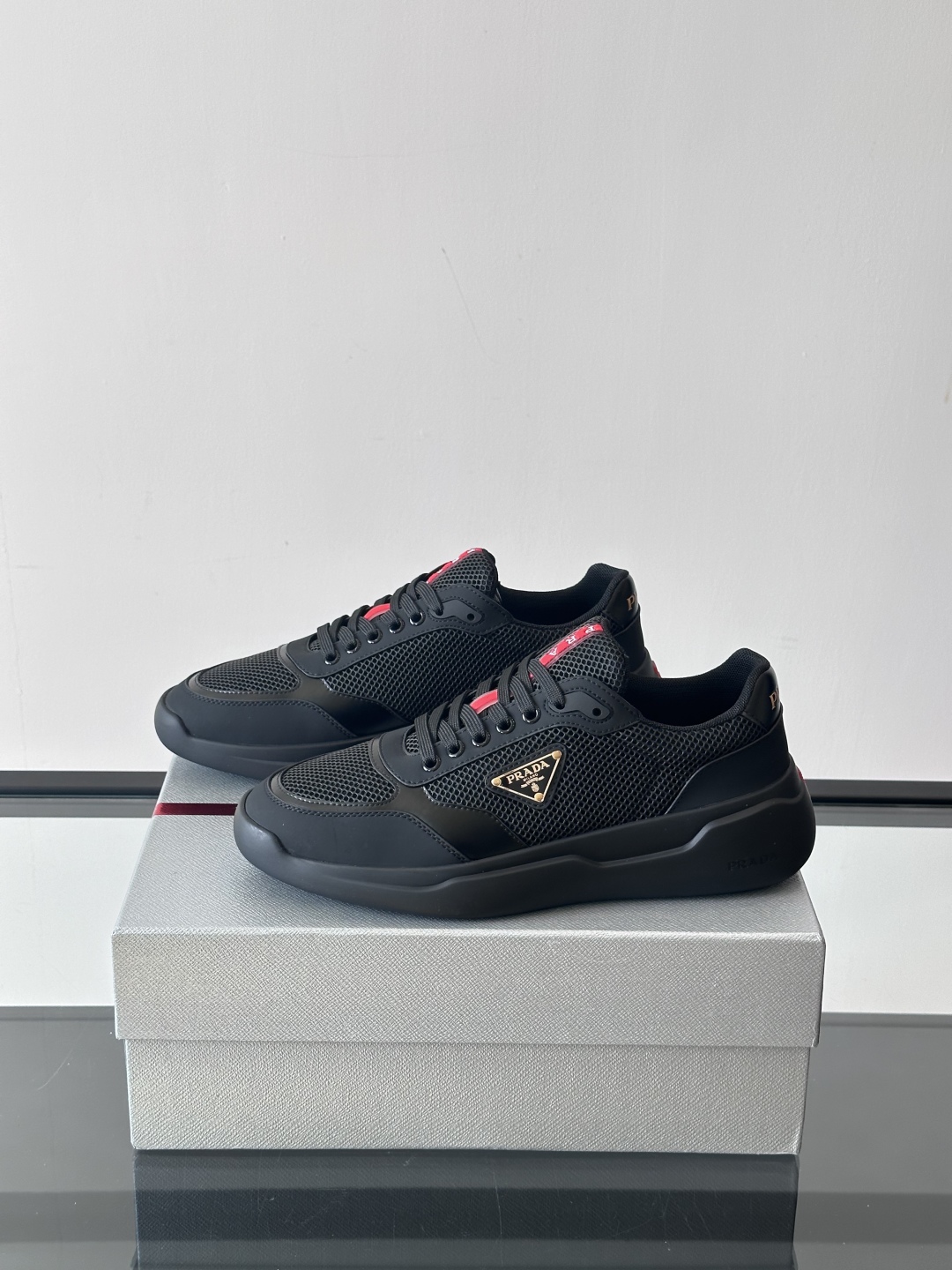 Prada/普拉达 男士新款运动休闲鞋，这款运动鞋鞋面采用进口小牛皮拼接透气网面，外侧饰以P家经典金属三