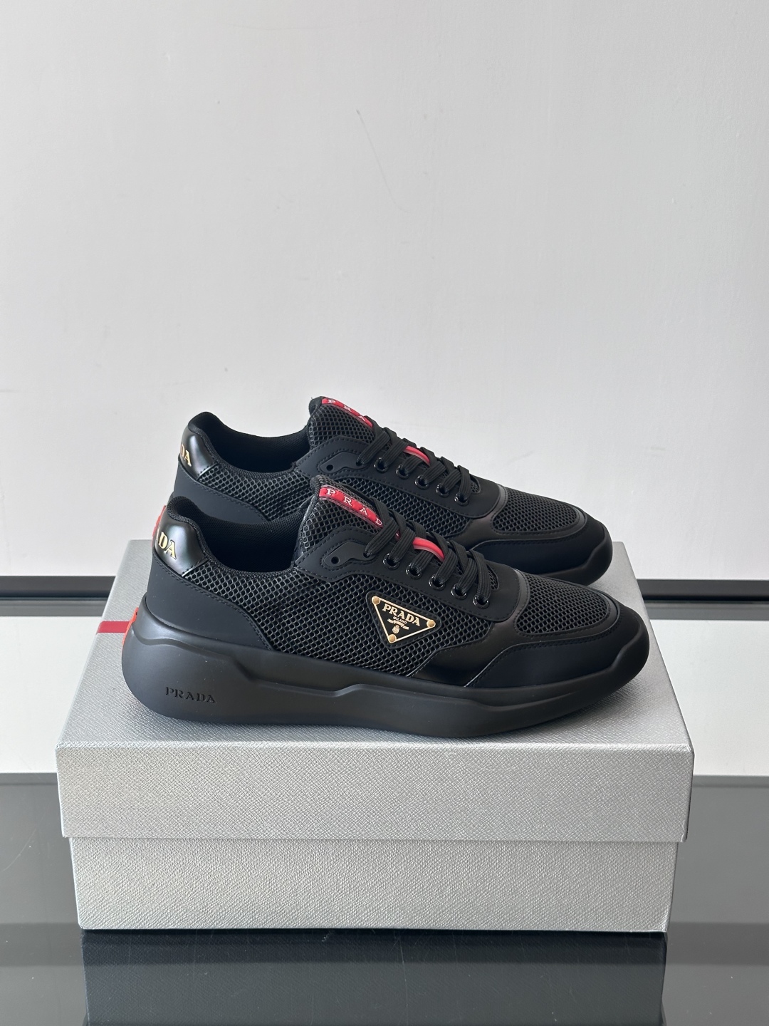 Prada/普拉达 男士新款运动休闲鞋，这款运动鞋鞋面采用进口小牛皮拼接透气网面，外侧饰以P家经典金属三