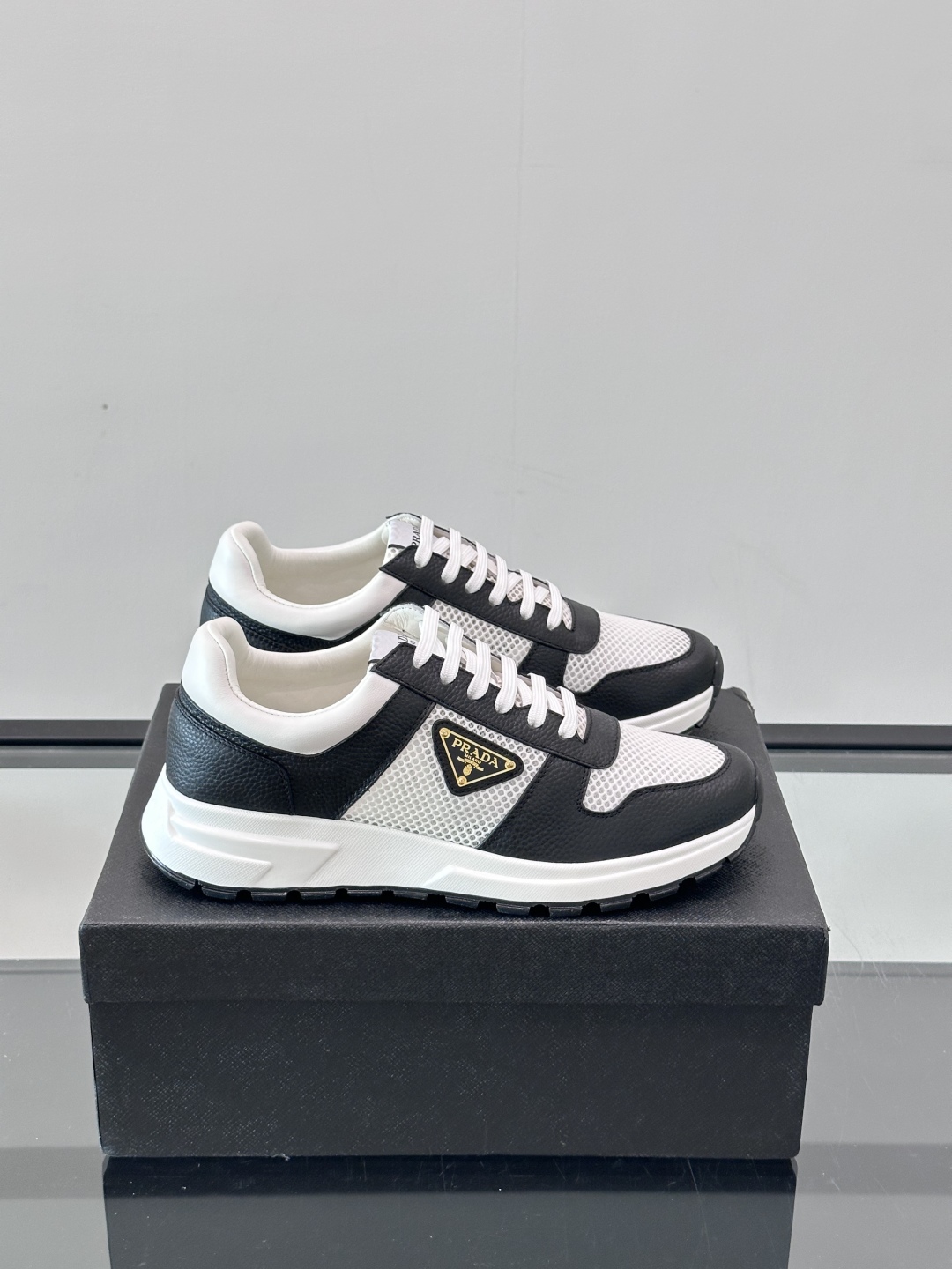 Prada/普拉达 男士新款运动休闲鞋，这款运动鞋鞋面采用进口小牛皮拼接透气网面，外侧饰以P家经典金属三