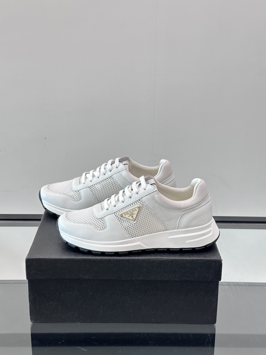 Prada/普拉达 男士新款运动休闲鞋，这款运动鞋鞋面采用进口小牛皮拼接透气网面，外侧饰以P家经典金属三