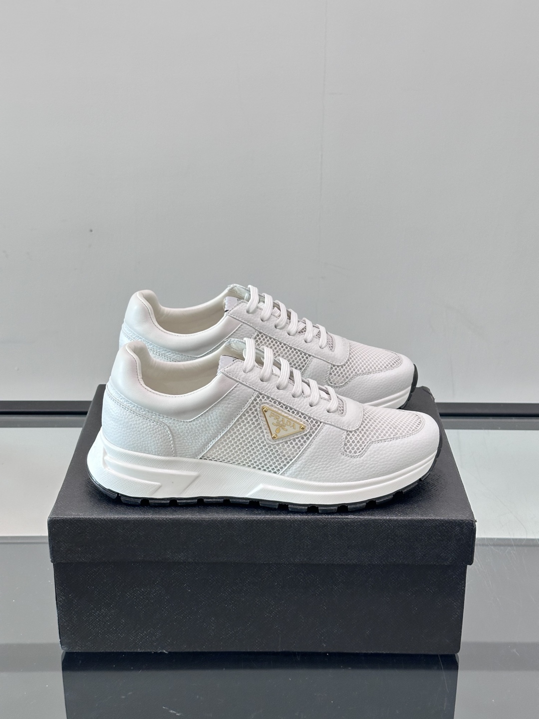 Prada/普拉达 男士新款运动休闲鞋，这款运动鞋鞋面采用进口小牛皮拼接透气网面，外侧饰以P家经典金属三