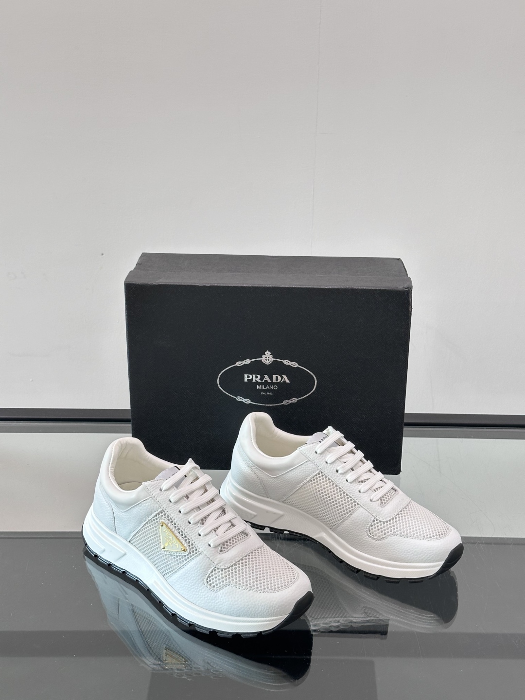 Prada/普拉达 男士新款运动休闲鞋，这款运动鞋鞋面采用进口小牛皮拼接透气网面，外侧饰以P家经典金属三