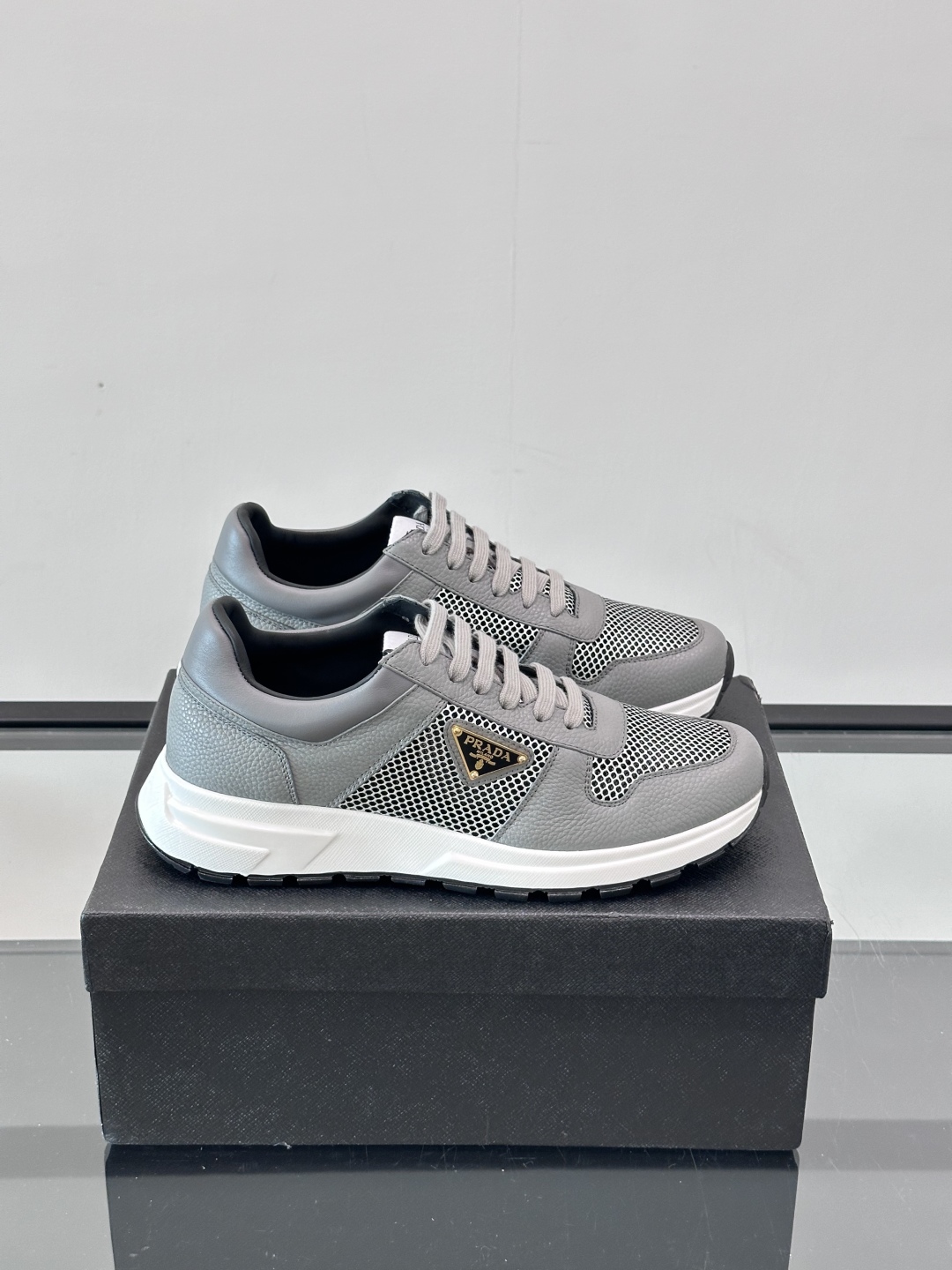 Prada/普拉达 男士新款运动休闲鞋，这款运动鞋鞋面采用进口小牛皮拼接透气网面，外侧饰以P家经典金属三