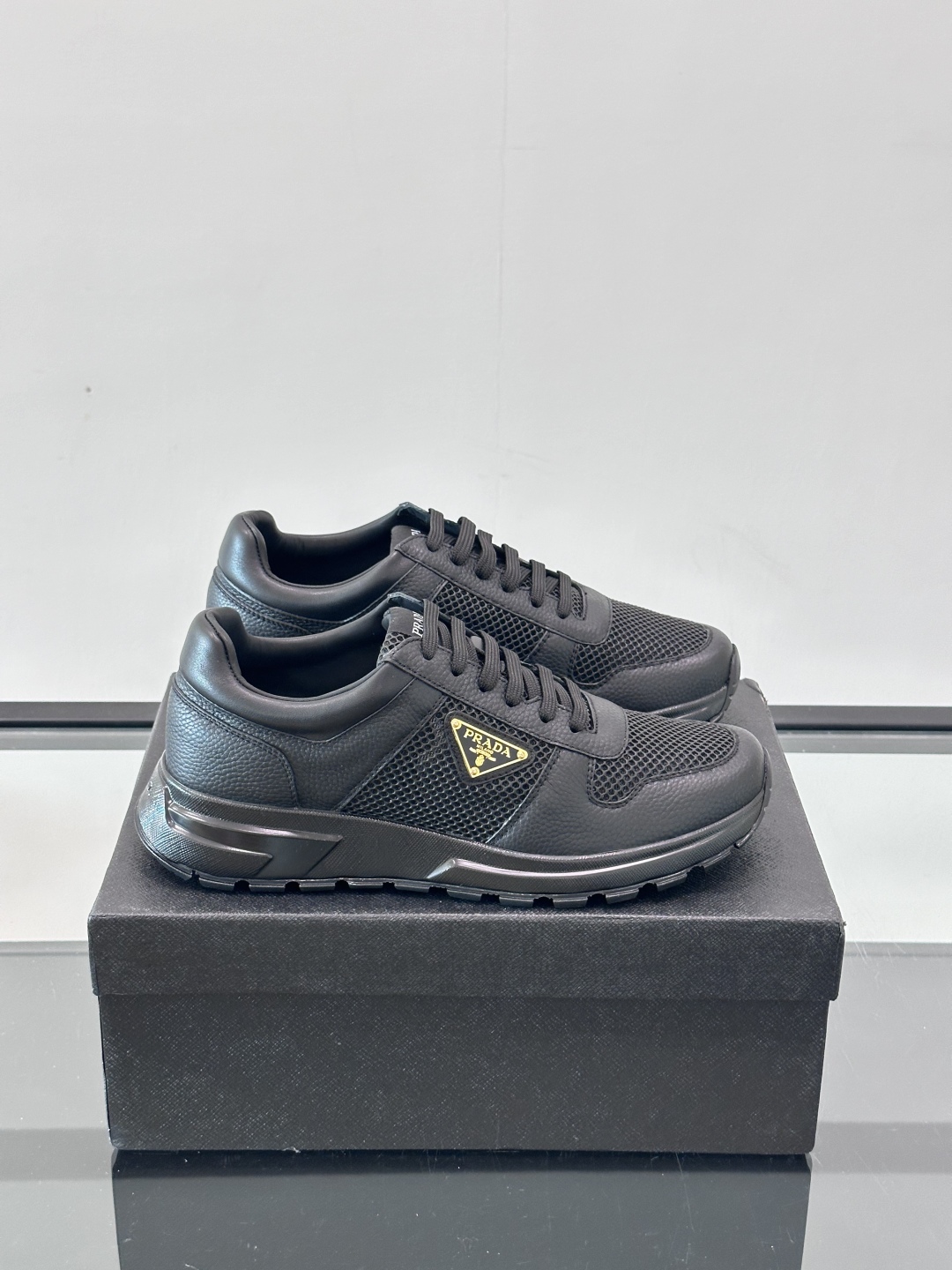 Prada/普拉达 男士新款运动休闲鞋，这款运动鞋鞋面采用进口小牛皮拼接透气网面，外侧饰以P家经典金属三