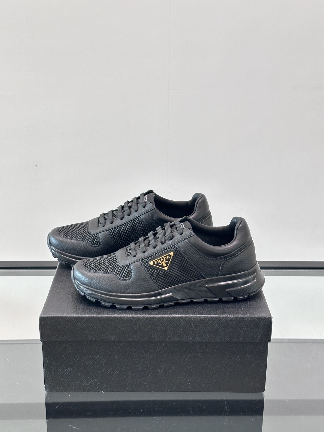 Prada/普拉达 男士新款运动休闲鞋，这款运动鞋鞋面采用进口小牛皮拼接透气网面，外侧饰以P家经典金属三