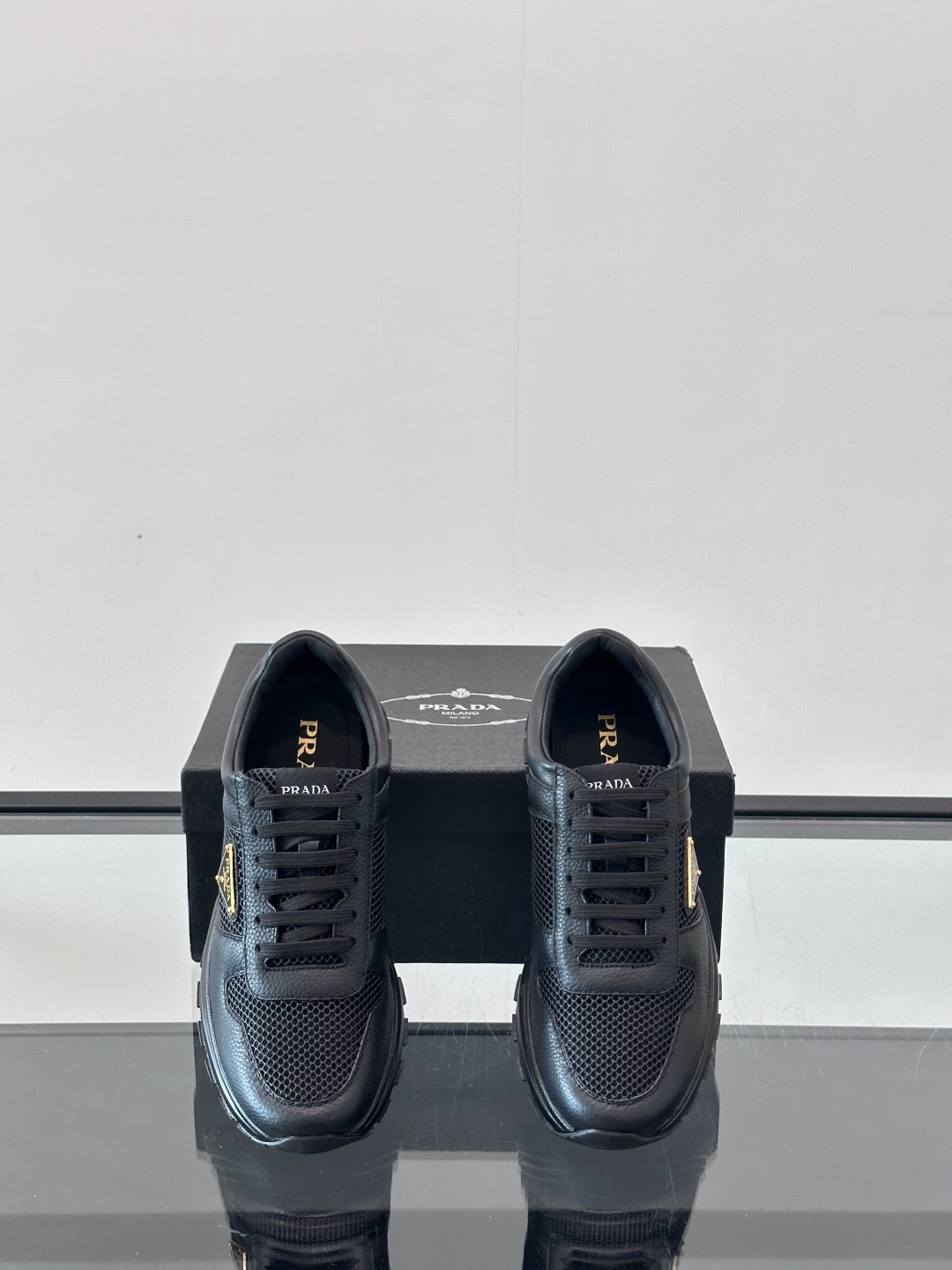Prada/普拉达 男士新款运动休闲鞋，这款运动鞋鞋面采用进口小牛皮拼接透气网面，外侧饰以P家经典金属三