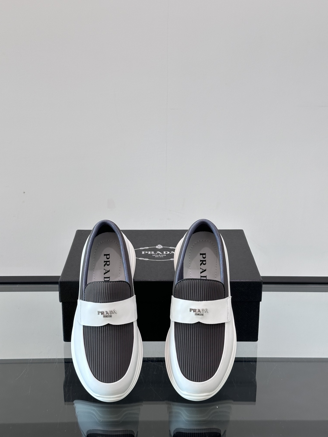 Prada/普拉达 男士新款一脚蹬懒人休闲鞋👟这款运动鞋采用光滑小牛皮革和摔纹牛皮拼接鞋面，一脚蹬乐福鞋