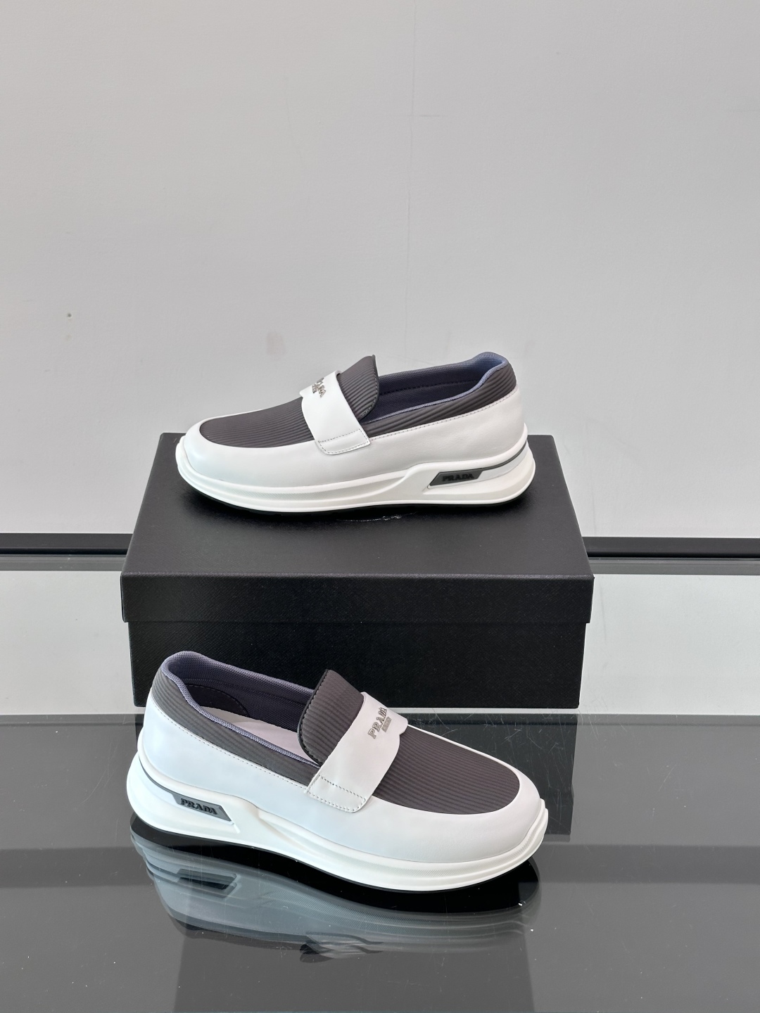 Prada/普拉达 男士新款一脚蹬懒人休闲鞋👟这款运动鞋采用光滑小牛皮革和摔纹牛皮拼接鞋面，一脚蹬乐福鞋