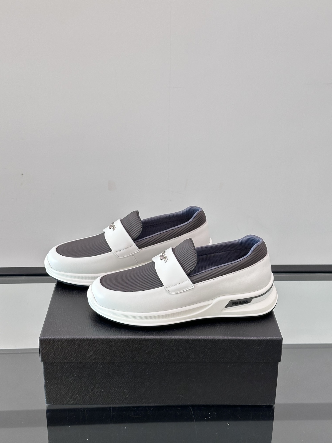 Prada/普拉达 男士新款一脚蹬懒人休闲鞋👟这款运动鞋采用光滑小牛皮革和摔纹牛皮拼接鞋面，一脚蹬乐福鞋