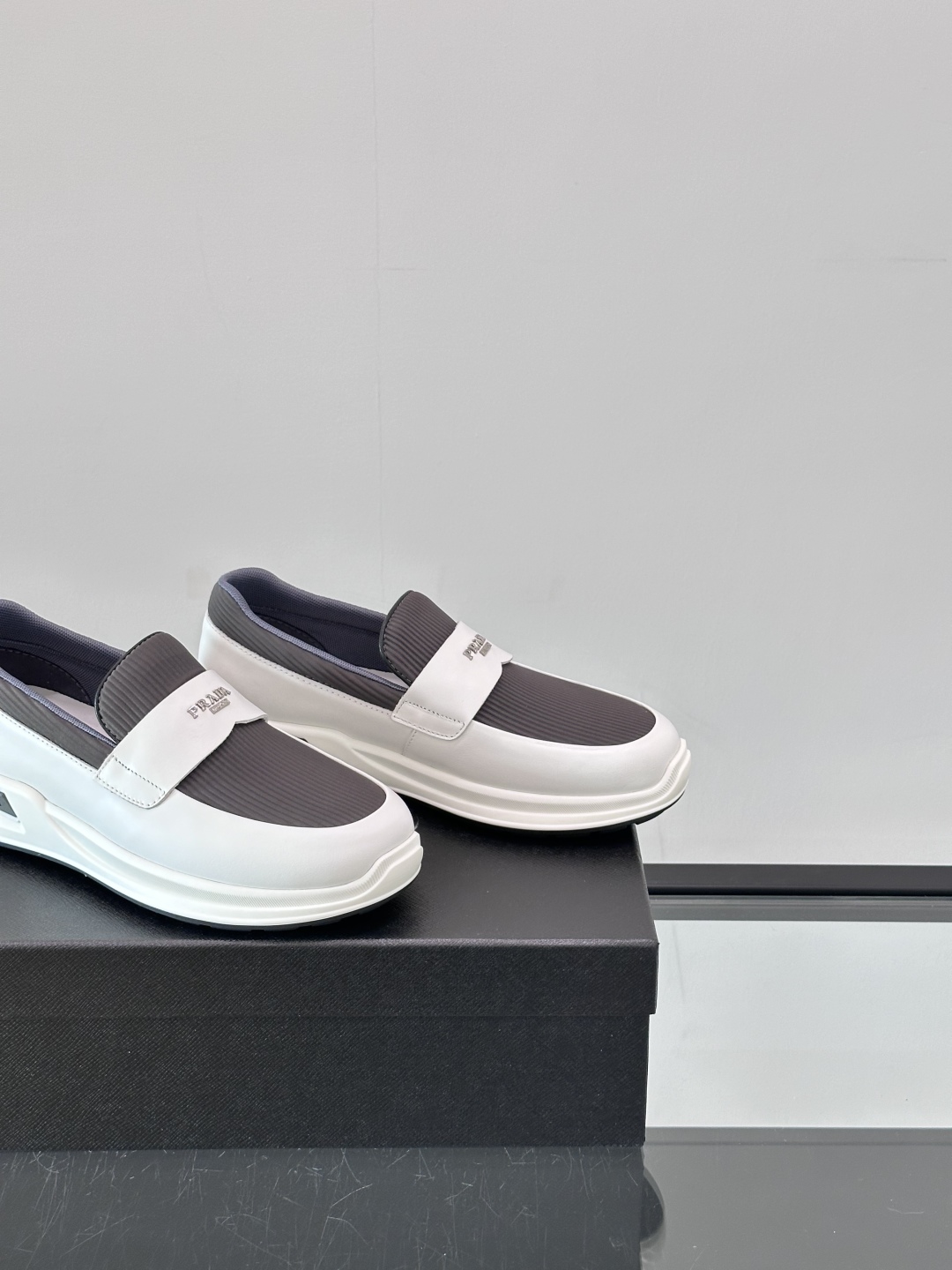 Prada/普拉达 男士新款一脚蹬懒人休闲鞋👟这款运动鞋采用光滑小牛皮革和摔纹牛皮拼接鞋面，一脚蹬乐福鞋