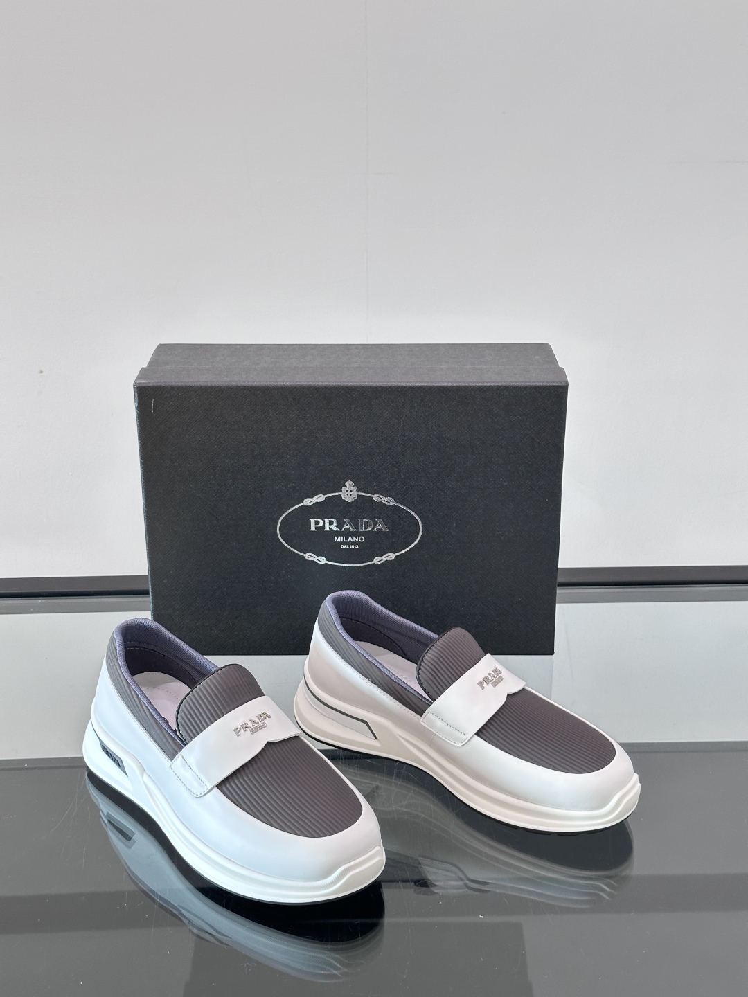 Prada/普拉达 男士新款一脚蹬懒人休闲鞋👟这款运动鞋采用光滑小牛皮革和摔纹牛皮拼接鞋面，一脚蹬乐福鞋