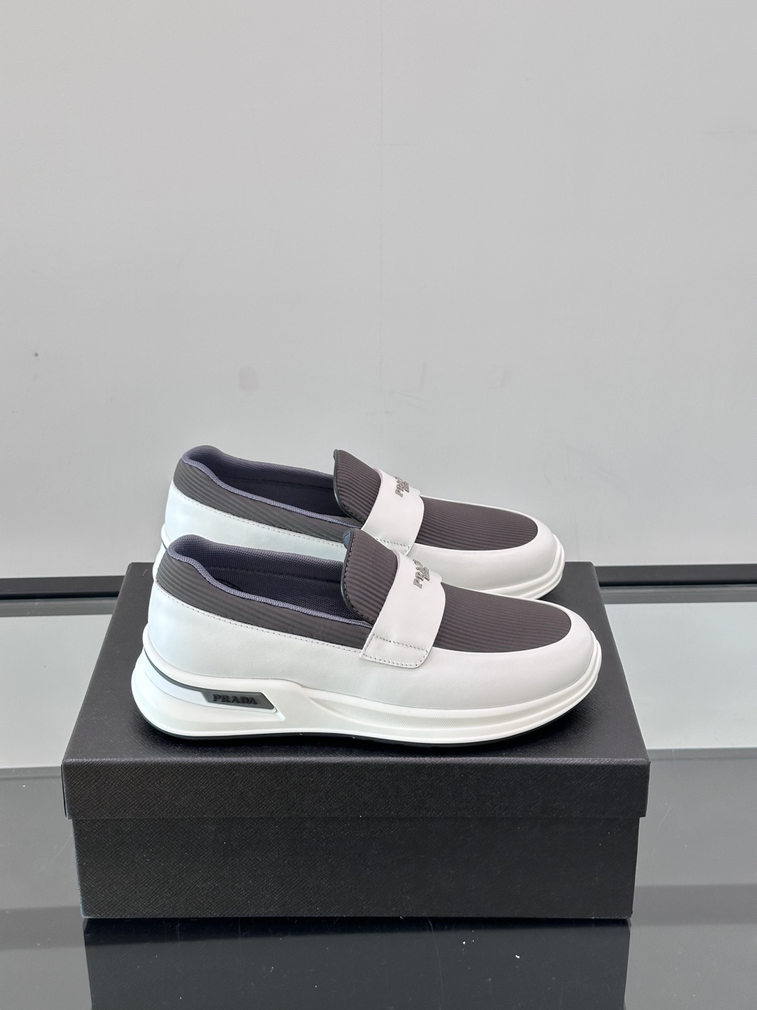 Prada/普拉达 男士新款一脚蹬懒人休闲鞋👟这款运动鞋采用光滑小牛皮革和摔纹牛皮拼接鞋面，一脚蹬乐福鞋