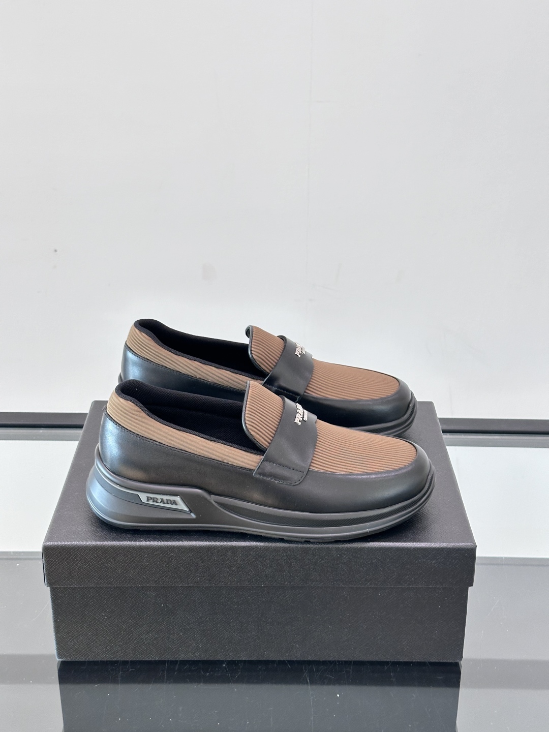 Prada/普拉达 男士新款一脚蹬懒人休闲鞋👟这款运动鞋采用光滑小牛皮革和摔纹牛皮拼接鞋面，一脚蹬乐福鞋