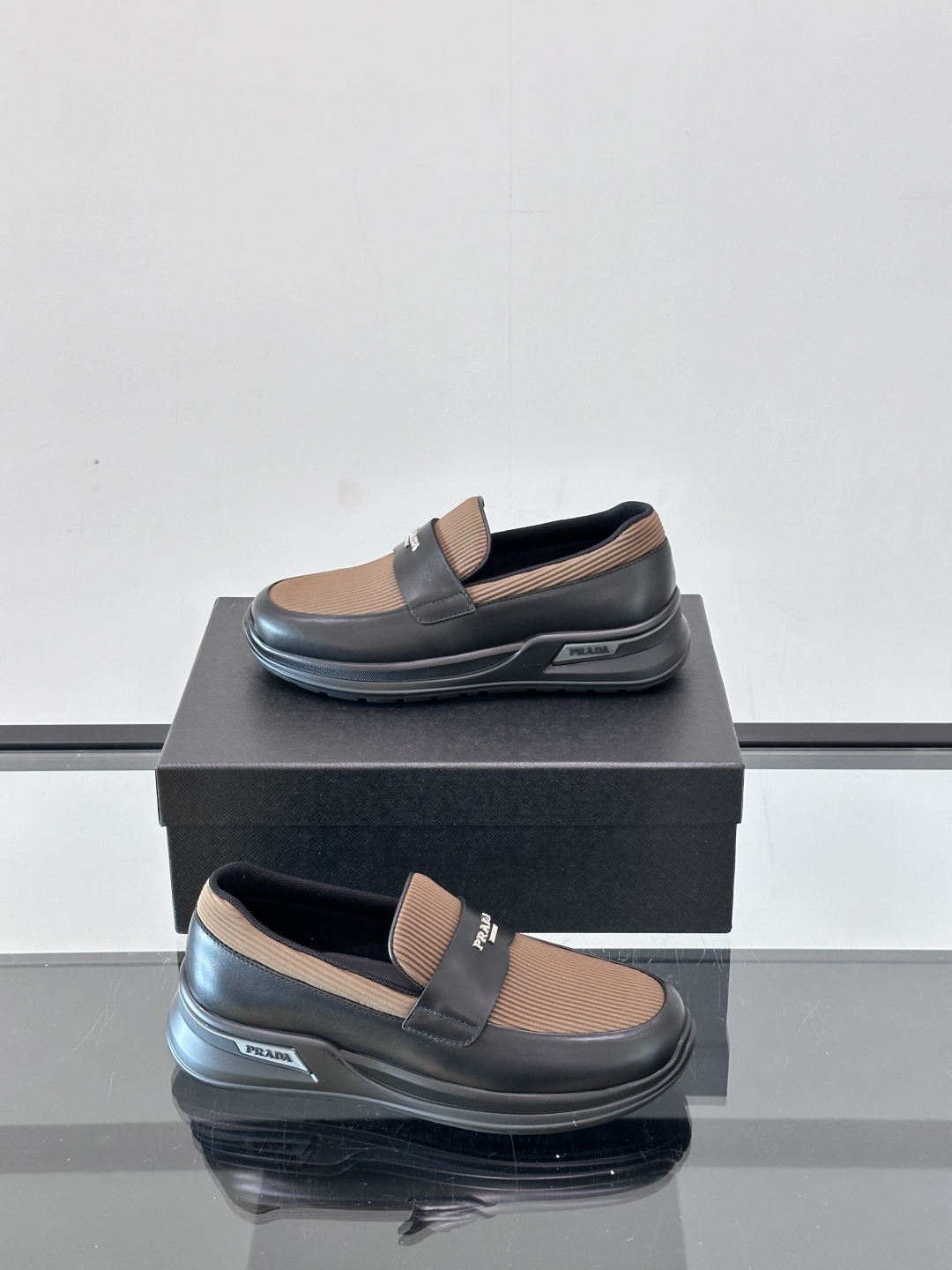 Prada/普拉达 男士新款一脚蹬懒人休闲鞋👟这款运动鞋采用光滑小牛皮革和摔纹牛皮拼接鞋面，一脚蹬乐福鞋