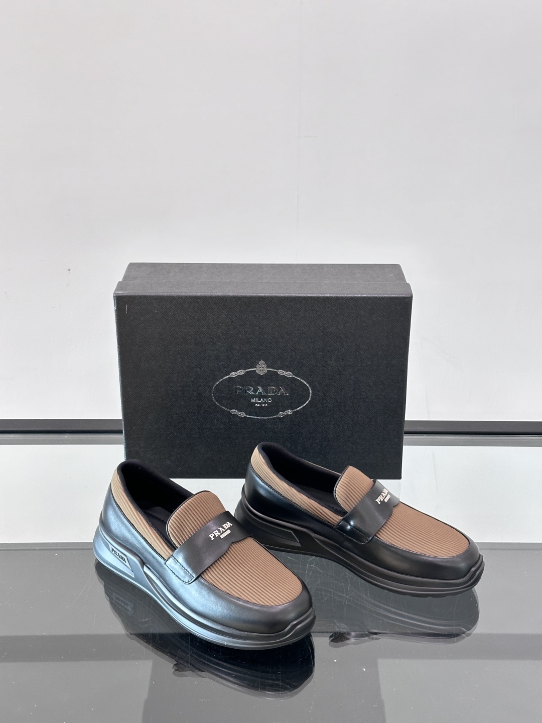 Prada/普拉达 男士新款一脚蹬懒人休闲鞋👟这款运动鞋采用光滑小牛皮革和摔纹牛皮拼接鞋面，一脚蹬乐福鞋