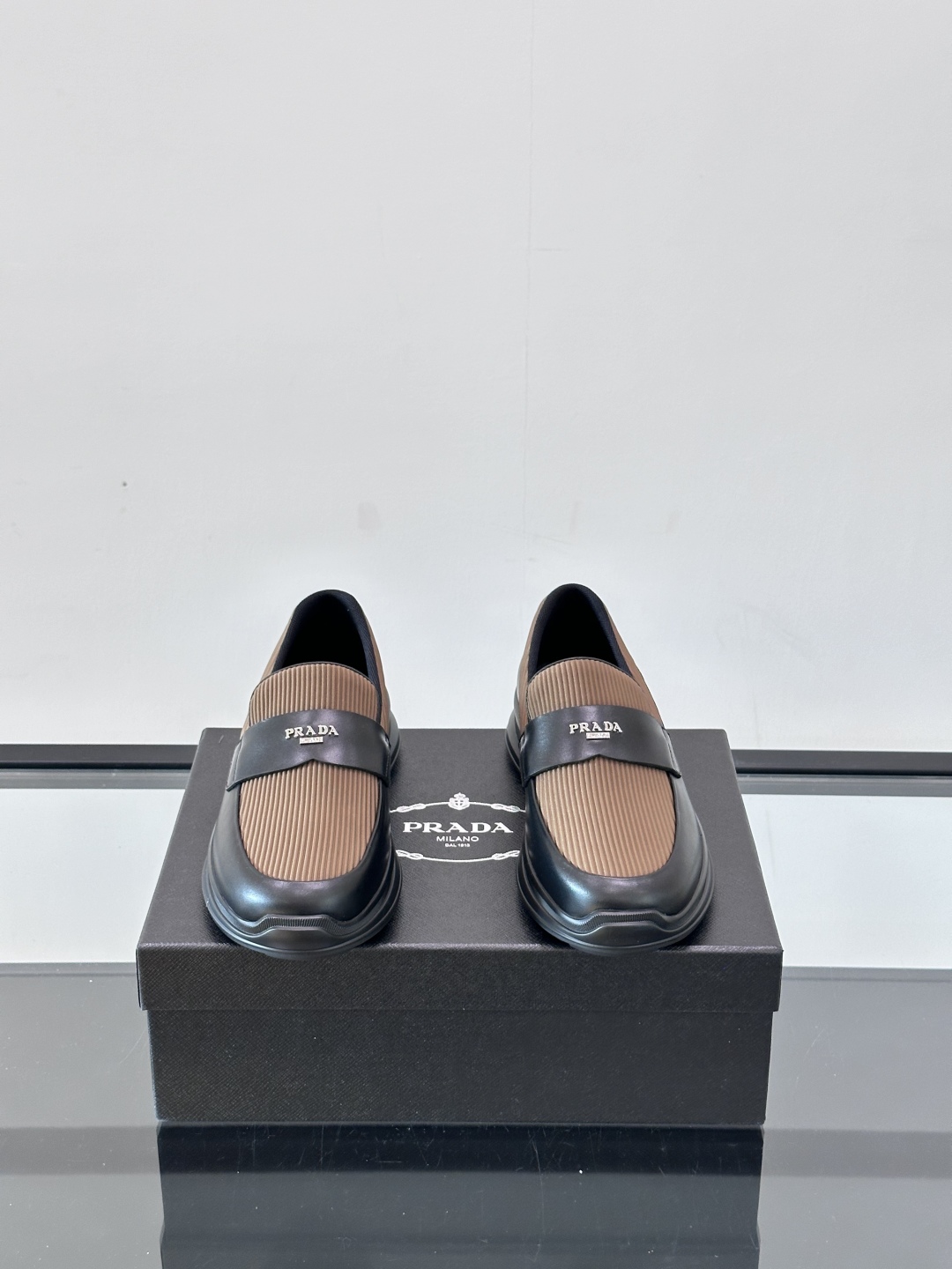 Prada/普拉达 男士新款一脚蹬懒人休闲鞋👟这款运动鞋采用光滑小牛皮革和摔纹牛皮拼接鞋面，一脚蹬乐福鞋