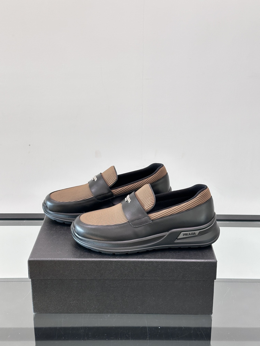 Prada/普拉达 男士新款一脚蹬懒人休闲鞋👟这款运动鞋采用光滑小牛皮革和摔纹牛皮拼接鞋面，一脚蹬乐福鞋