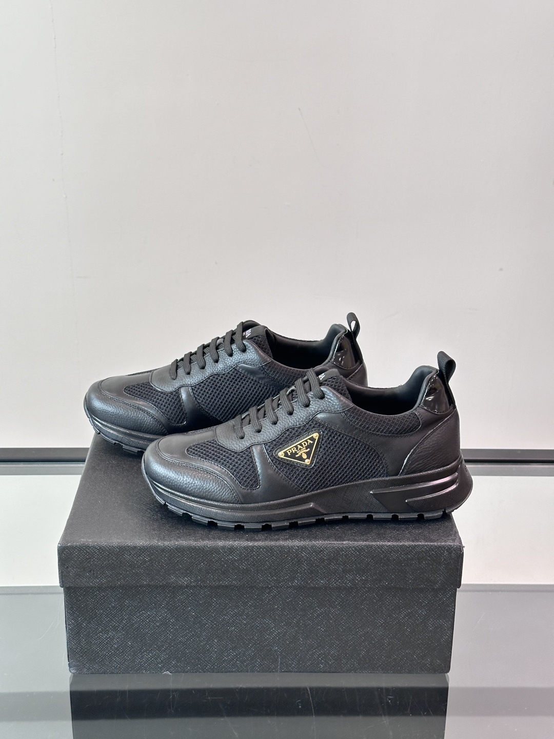 Prada/普拉达 男士新款运动休闲鞋，这款运动鞋鞋面采用进口小牛皮拼接透气网面，外侧饰以P家经典金属三