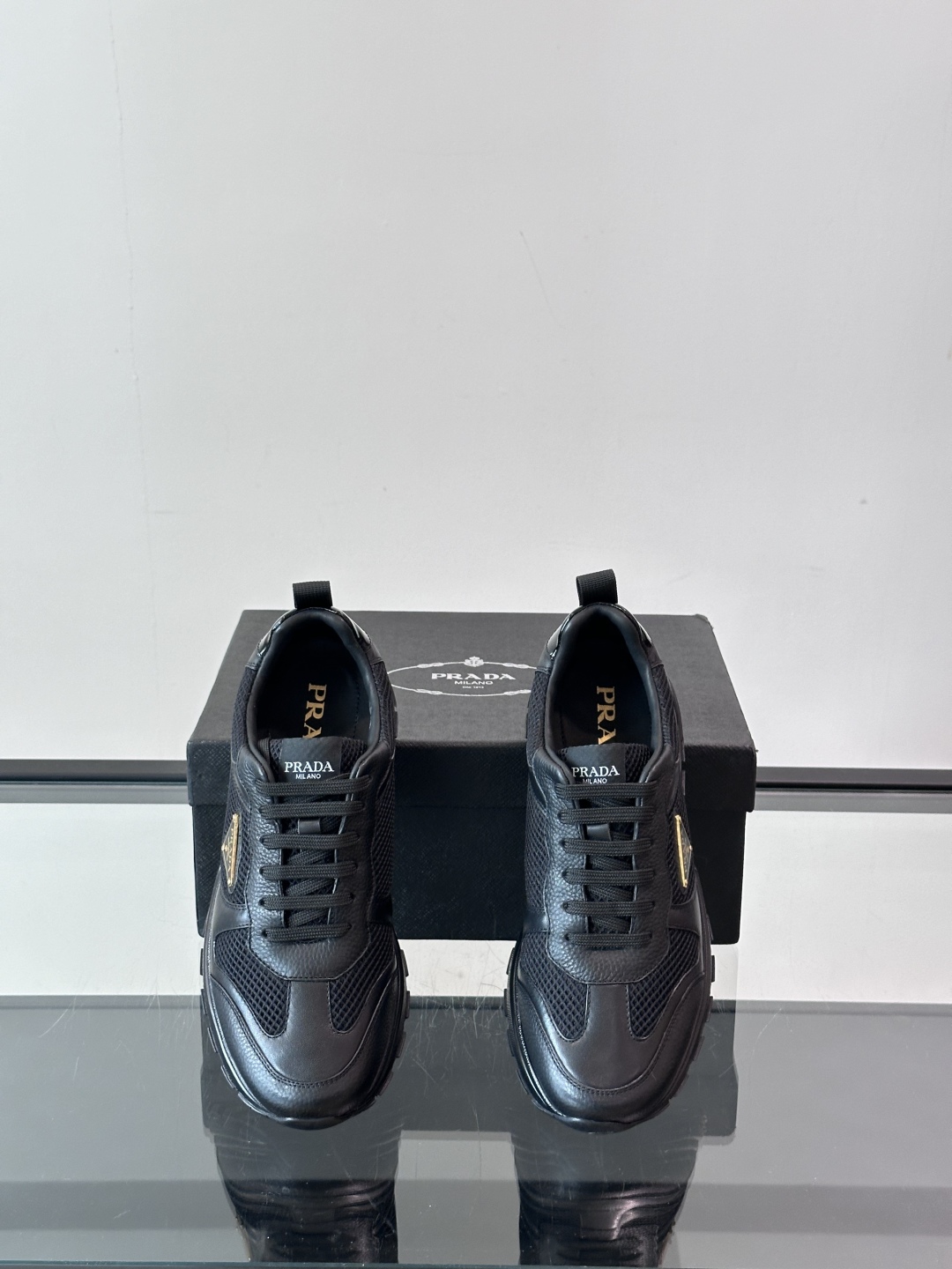 Prada/普拉达 男士新款运动休闲鞋，这款运动鞋鞋面采用进口小牛皮拼接透气网面，外侧饰以P家经典金属三