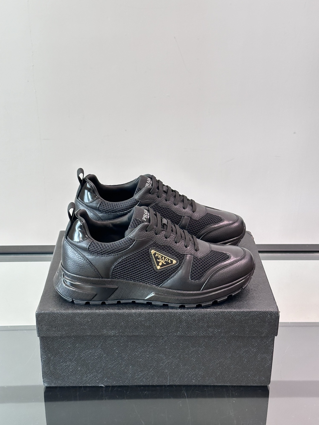 Prada/普拉达 男士新款运动休闲鞋，这款运动鞋鞋面采用进口小牛皮拼接透气网面，外侧饰以P家经典金属三