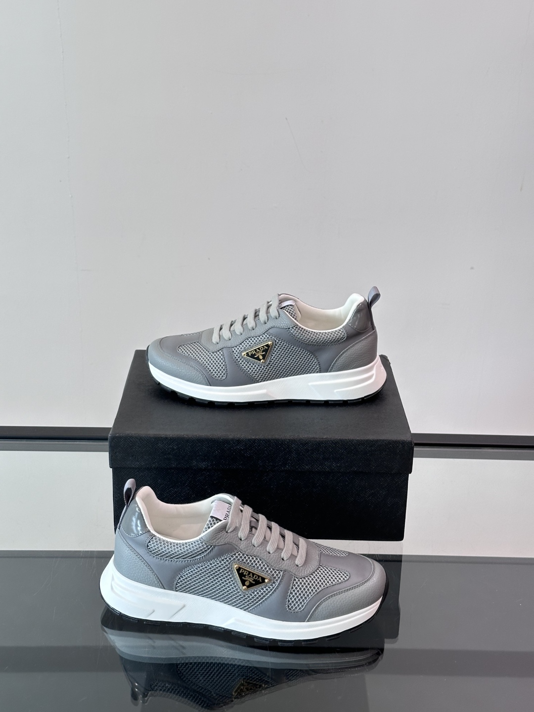 Prada/普拉达 男士新款运动休闲鞋，这款运动鞋鞋面采用进口小牛皮拼接透气网面，外侧饰以P家经典金属三