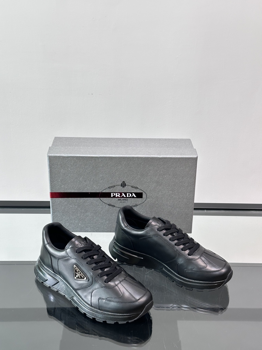 Prada/普拉达 男士新款运动休闲鞋，这款运动鞋鞋面采用进口小牛皮。外侧饰以P家经典金属三角珐琅徽标，