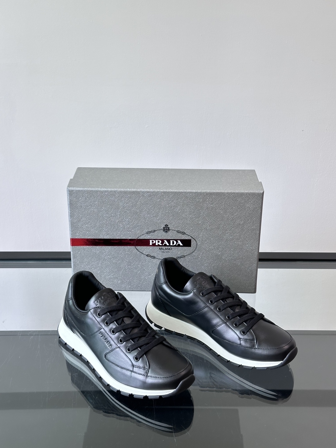Prada/普拉达 男士新款运动休闲鞋，这款运动鞋鞋面采用进口小牛皮。外侧饰以P家经典金属三角珐琅徽标，