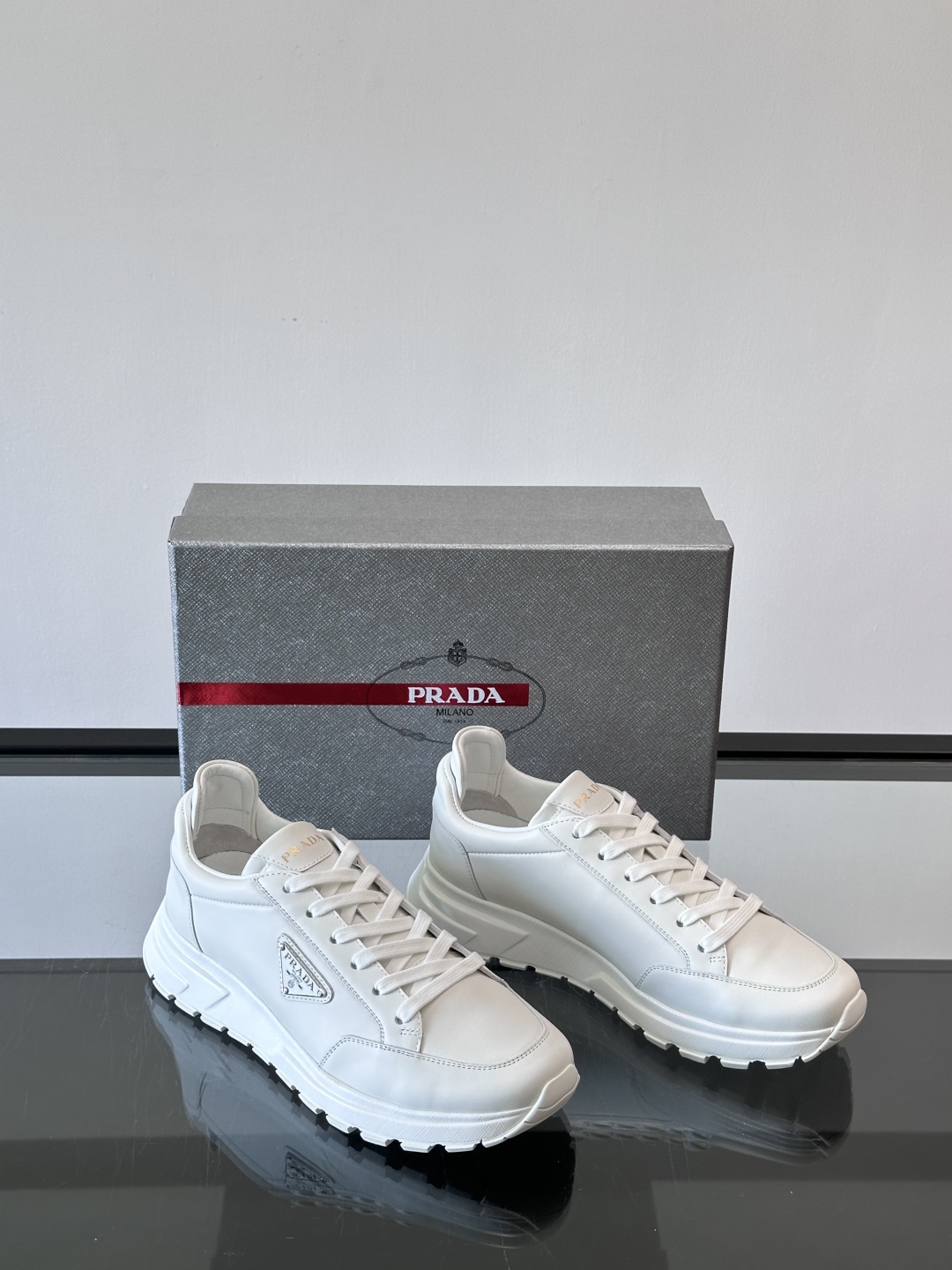 Prada/普拉达 男士新款运动休闲鞋，这款运动鞋鞋面采用进口小牛皮。外侧饰以P家经典金属三角珐琅徽标，