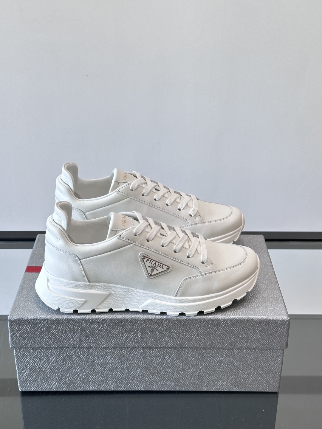 Prada/普拉达 男士新款运动休闲鞋，这款运动鞋鞋面采用进口小牛皮。外侧饰以P家经典金属三角珐琅徽标，